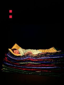 Frau liegt auf einem Stapel bunter Decken